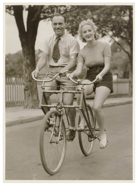 Man_and_woman_on_a_Malvern_Star_abreast_tandem_bicycle,_c._1930s,_by_Sam_Hood